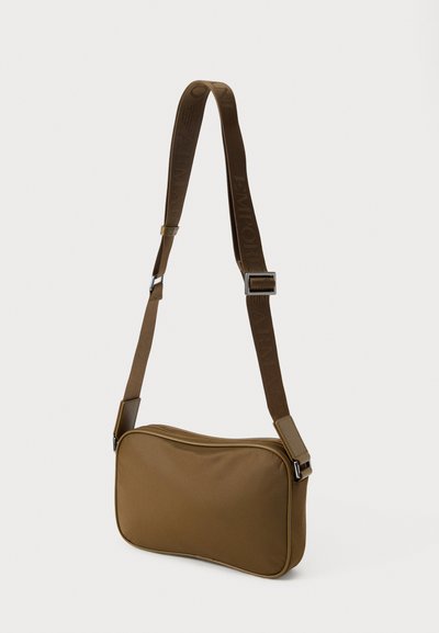 Καφέ ορθογώνια τσάντα ώμου με ρυθμιζόμενο λουράκι, εμφανίζει το ανάγλυφο όνομα της μάρκας, λεία υφή και κλείσιμο με φερμουάρ.