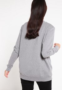 Grå sweatshirt, långa ärmar, ribbade muddar och fåll, avslappnad passform, mjuk bomullsblandningsmaterial, enkel design utan mönster eller accenter.