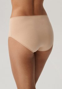 Beżowe bawełniane majtki o gładkiej fakturze, średnim stanie i miękkim pasku, widoczne z tyłu, bez widocznych szwów.