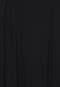 Zwarte stof met een zachte textuur, met subtiele drapeerdetails, waardoor een vloeiende silhoeët ontstaat zonder patronen of accenten.