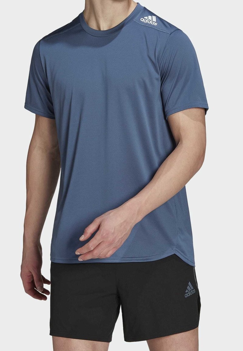 T-shirt de sport bleu en tissu respirant avec un motif texturé, présentant des manches courtes et un logo sur l'épaule. Associé à un short noir.