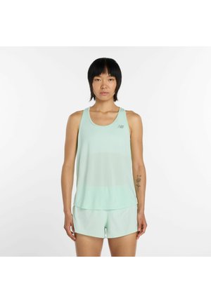 Vrouw met kort zwart haar draagt een lichtgroen mouwloos sporttopje en bijpassende shorts, staand tegen een witte achtergrond.
