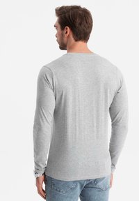 Grijze longsleeve t-shirt van katoenmix, met ronde hals en een gladde textuur, gedragen met lichtblauwe spijkerbroek.