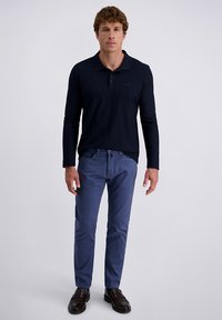 Dunkelblaues Langarm-Polo mit Kragen, kombiniert mit hellblauen Slim-Fit-Hosen und dunkelbraunen Slippern. Schlichtes Design, glatte Textur.