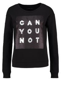 Sudadera negra con una textura suave que presenta un parche rectangular de lentejuelas que muestra las palabras "¿NO PUEDES?" en letras blancas.