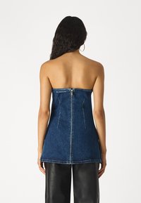 Dunkelblaues, trägerloses Denim-Oberteil mit Reißverschluss und Logodetail am Ausschnitt, das ein strukturiertes Design und Nahtakzente aufweist.