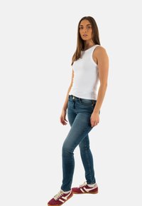 Top a righe bianco, jeans skinny blu e scarpe da ginnastica bordeaux con accenti bianchi. Tessuto liscio e design aderente.