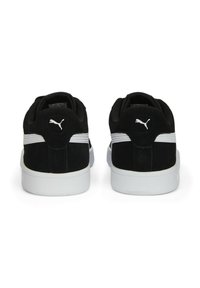 Une paire de baskets Puma noires avec des rayures et un logo blancs, vues de l'arrière, montrant des cols rembourrés et des semelles blanches.