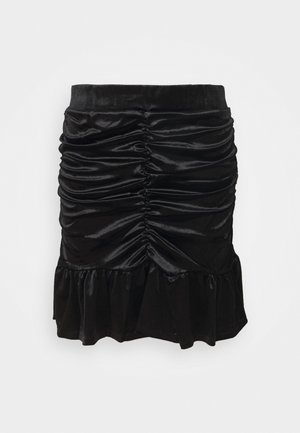 Zwarte fluwelen minirok met geplooide voorkant en gerimpelde zoom tegen een effen witte achtergrond.