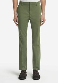 Gröna slim-fit-byxor i lätt tyg, med slät framsida, sidofickor och ren fåll, stylad med mörka snörskor.