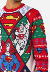 Sveter s motívom Supermana v červeno-zeleno-bielej farebnej kombinácii, zdobený výraznými pletenými grafikami Supermana v rôznych pózach a logách.