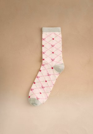 Fehér zokni szürke orr- és szegéllyel, rózsaszín és bézs rombmintával díszítve, piros szívekkel és kis piros masnikkal bézs alapon.
