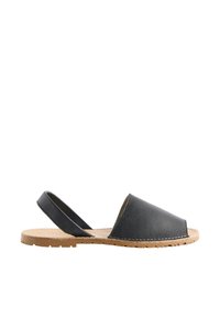 Sandale en cuir noir à bout ouvert avec une bride arrière et une semelle plate beige, vue de côté sur fond blanc.