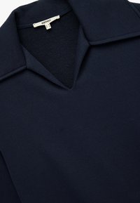 Top de color azul marino con cuello, con un diseño de escote en V, hecho de una tela suave con un cuello interior texturizado. Detalles de costura sutiles en toda la prenda.
