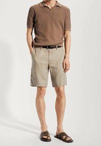 Braunes geripptes Poloshirt, beigefarbene Shorts, schwarzer Gürtel und braune Sandalen. Die Shorts haben eine lockere Passform und seitliche Taschen.