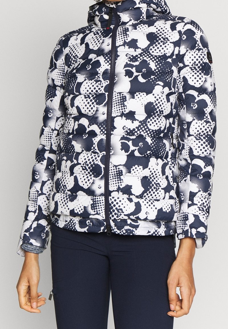 Laivastonsininen ja valkoinen untuvatakki, jossa on kukka- ja pilkkukuviot, vetoketjukiinnitys, huppu ja joustavat hihansuut. Valmistettu tikatusta, eristetystä kankaasta.