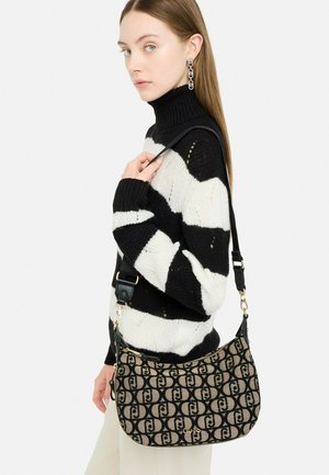 Borsa a tracolla in tessuto stampato con un design beige e nero, dotata di chiusura con zip, tracolla regolabile e dettagli dorati.