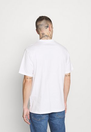 Camiseta blanca de algodón con mangas cortas, escote redondo y corte recto. Presenta un logotipo mínimo en el dobladillo.