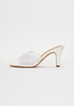 Mule bianche con tacco a spillo e punta aperta, dotate di un design in rete intrecciata e piccoli dettagli argentati. Finitura liscia, tacco sottile e forma arrotondata.