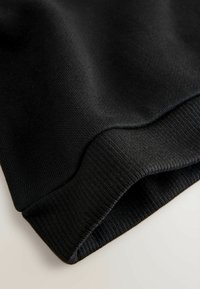Tessuto nero lavorato a maglia con una texture liscia, caratterizzato da un polsino a coste. Il design presenta una forma pulita e semplice con dettagli di cucitura discreti.
