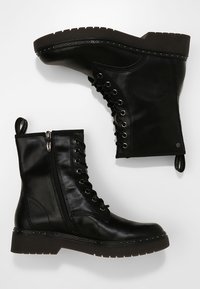 Zwarte leren enkelboots met een gestructureerde afwerking, vetersluiting aan de voorkant, zijrits en studs langs de zool. Platte rubberen zool.