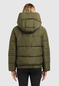 Veste matelassée vert olive avec une large capuche, des coutures horizontales et une ceinture élastique. Texture lisse et design décontracté.