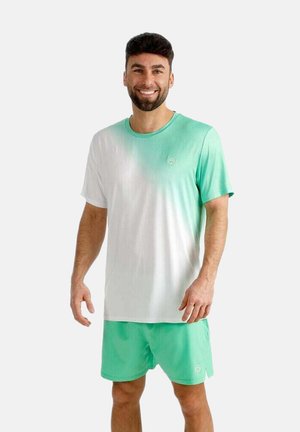 Man die glimlacht en een groen-wit ombre T-shirt met korte mouwen draagt, samen met bijpassende groene shorts, tegen een witte achtergrond.