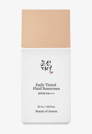 Tube de fluide solaire teinté quotidien, 50 mL, avec un contenant blanc et un couvercle pêche, étiqueté avec un texte noir et rouge, SPF30 PA+++