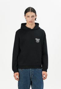 Black hooded sweatshirt with a front kangaroo pocket, ribbed cuffs, and a small white graphic logo on the left chest. Cotton blend material.