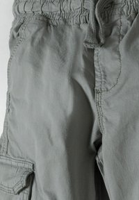 Grijze cargo shorts met een elastische tailleband en verstelbaar trekkoord, met zijzakken en zichtbare stikdetails.