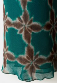 Transparenter Stoff mit einem türkisfarbenen Hintergrund und großen, weich gezeichneten braunen Blumenmustern, die symmetrische Formen bilden.