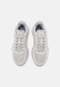 Para jasnoszarych butów sportowych Puma z białymi podeszwami, szarymi sznurówkami i subtelnym logo na języku, przedstawionych z widoku z góry na białym tle.