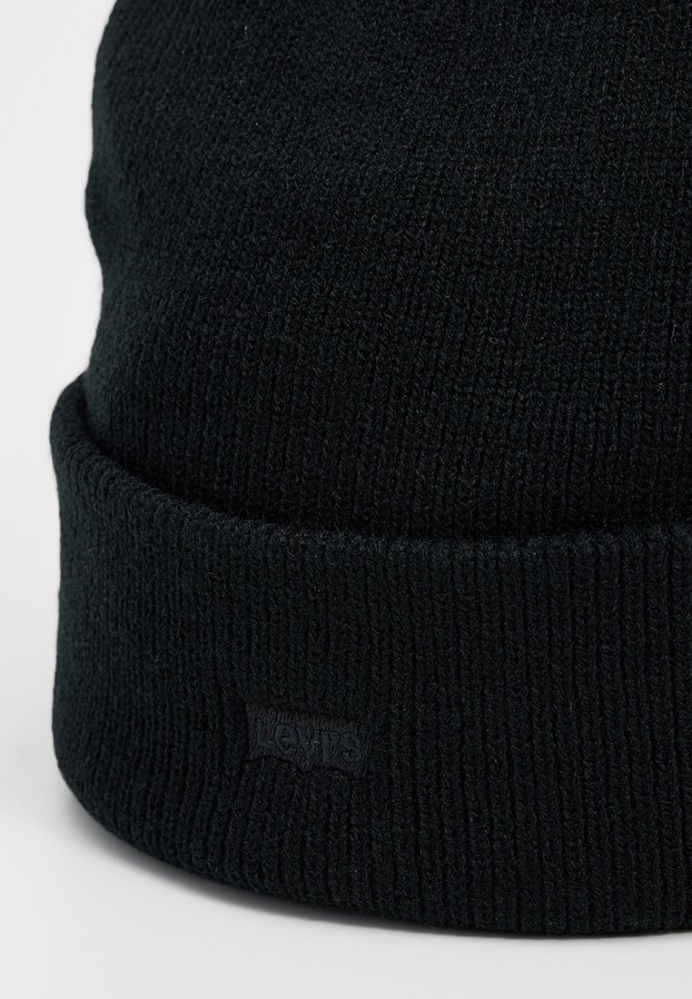 Bonnet en tricot noir en tissu doux, avec un bord replié et un patch logo Levi's discret cousu sur le côté. Design à côtes texturé.
