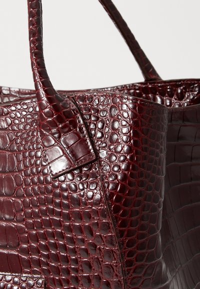 Τσάντα tote σε χρώμα μπορντό με ανάγλυφο σχέδιο κροκοδείλου, με υφή στην επιφάνεια, διπλούς ιμάντες και δομημένο σχέδιο, που παρουσιάζει λεπτομερή ραφή στα πλάγια.