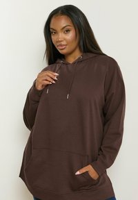 Felpa con cappuccio marrone dotata di tasca frontale, maniche lunghe e cordino. Tessuto morbido e vestibilità rilassata, adatta per un abbigliamento casual.