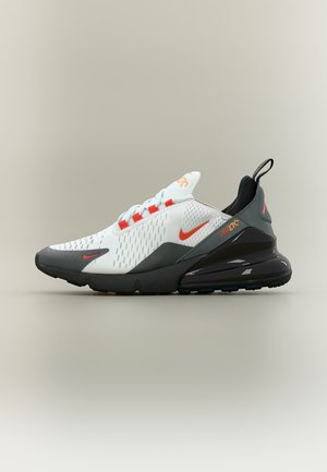 Baskets blanches et grises Nike Air Max 270 avec des accents orange, semelle noire et coussin d'air arrière visible, vues de profil sur un fond neutre.