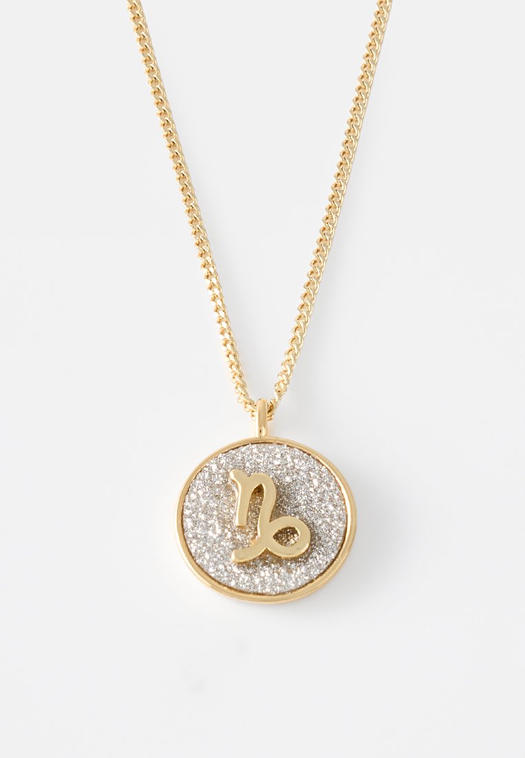 Collana d'oro con pendente rotondo, caratterizzato da uno sfondo argento luccicante e un simbolo zodiacale del Capricorno in oro al centro.