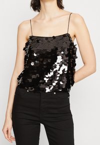 Czarna koszulka na ramiączkach ozdobiona cekinami, z cienkimi ramiączkami, o luźnym kroju i odbijającymi okrągłymi cekinami tworzącymi błyszczący efekt.