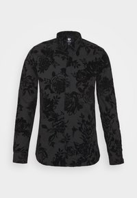 Zwarte button-up shirt met bloemenpatroon, gemaakt van gestructureerde stof. Bevat een puntige kraag en lange mouwen met knoopmanchetten.