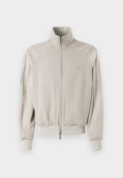 Ανοιχτό γκρι σακάκι με ψηλό γιακά, πλήρες φερμουάρ, ριχτές μανσέτες και στρίφωμα. Διαθέτει υφασμάτινη υφή και κατακόρυφες ρίγες στα μανίκια.