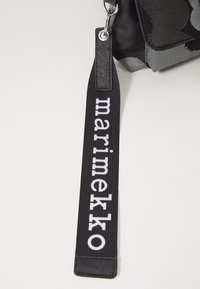 Black fabric bag strap featuring "marimekko" in white text. The strap has a smooth texture and a rectangular design with a clip for attachment.