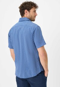 Camicia a maniche corte a righe blu con colletto a punta. Righe verticali in diverse tonalità di blu, materiale in cotone e vestibilità comoda.