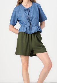 Top in denim a peplo con maniche corte e cintura annodata sul davanti, abbinato a pantaloni corti con elastico in vita di colore verde oliva. Design semplice e casual, senza motivi.