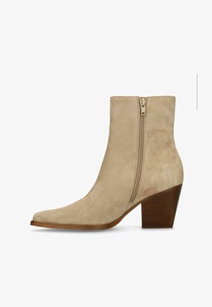 Bottine en daim beige avec fermeture éclair latérale, bout pointu et talon bloc en bois empilé.