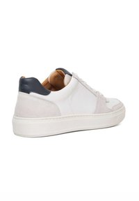 White leather sneaker with grey suede accents and a navy heel cap. Features white laces and a textured rubber sole.