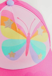 Casquette de baseball rose ornée d'un papillon en nuances pastel et d'étoiles dorées. Fabriquée en tissu avec une texture lisse et une forme arrondie.