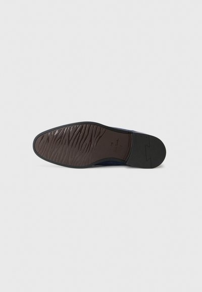 Semelle de chaussure avec une texture ondulée brune, bordée d'un edge noir. Le dessous comprend des détails du modèle embossés dans le caoutchouc.