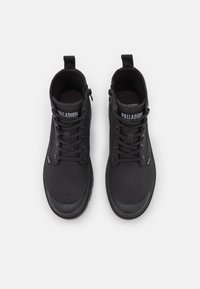 Bottines montantes noires en toile avec embouts en caoutchouc, fermeture à lacets à l'avant et fermeture éclair sur le côté. Logo "PALLADIUM" sur la languette.