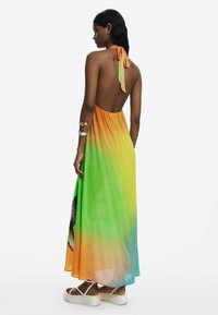 Maxi dress with a halter neckline, featuring a gradient from orange to green, made of lightweight fabric. Backless design, ankle-length.