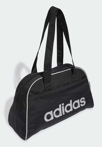 Musta duffel-laukku, joka on valmistettu kestävästä kankaasta, pyöreän muotoinen, paksut mustat hihnat, valkoinen pipingin reuna ja näyttävä harmaa "adidas" logo.